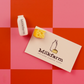 Milkfarm branding with a cheese block and bottle magnet on a red and pink checkered background