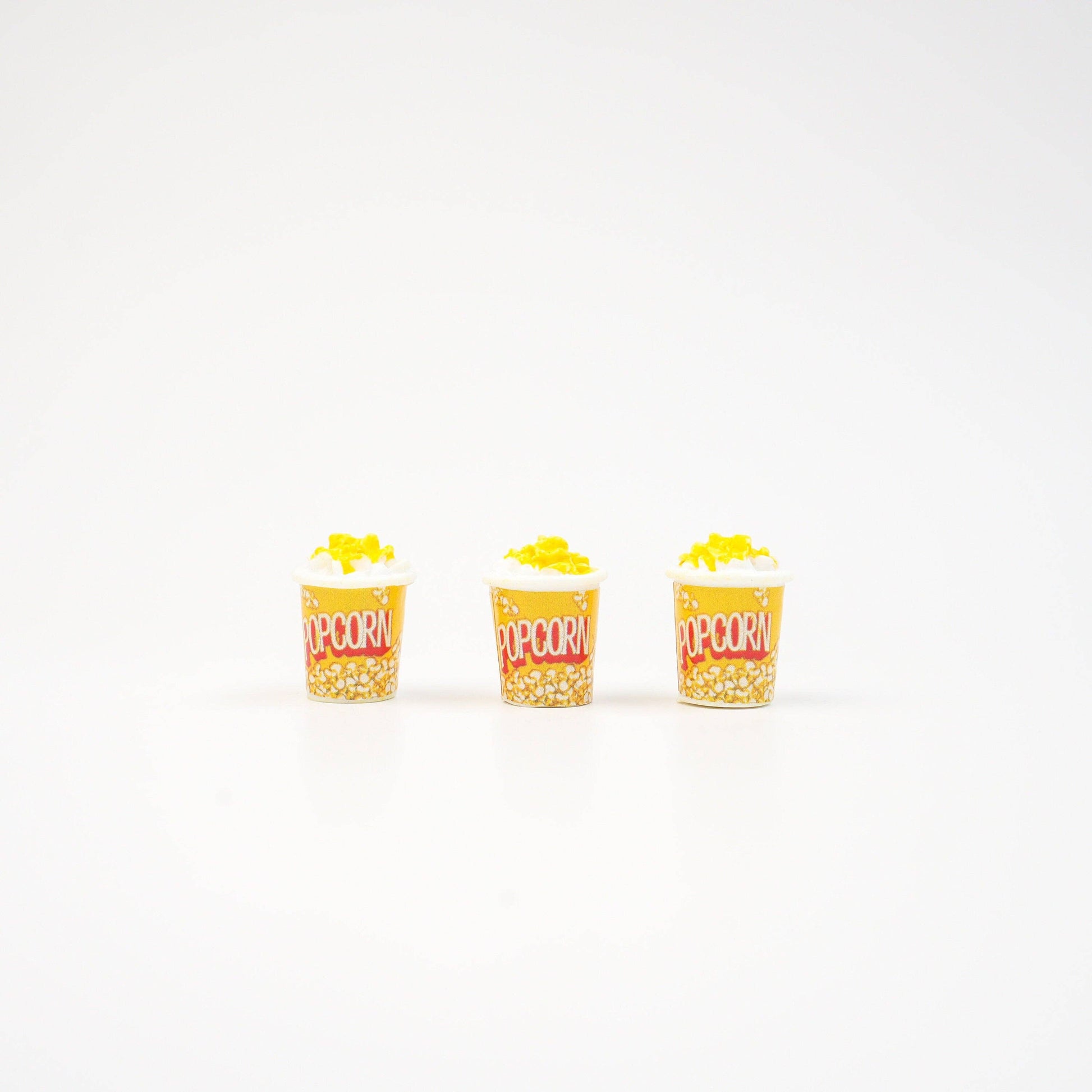 Three mini popcorn magnets standing in a row.