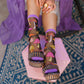 Person wearing colorful mushroom socks with platform sandals on a textured floor.