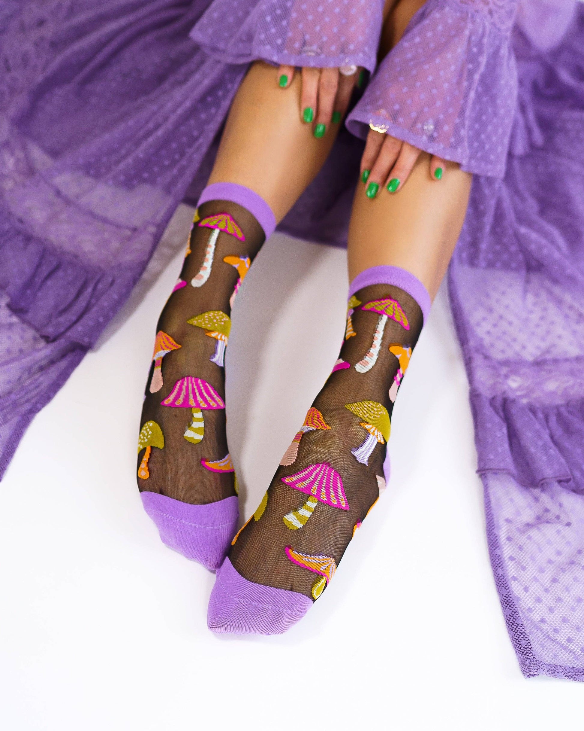 Sheer socks with mushroom pattern worn by a person in a purple outfit.