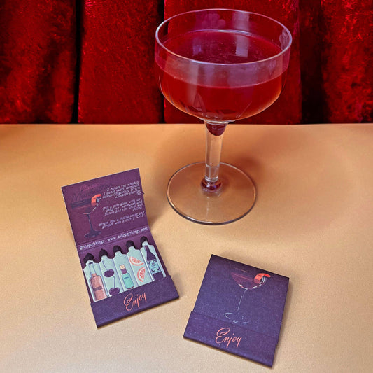 two manhattan matchbooks pictured with a manhattan cocktail. One matchbook is open and the other is closed