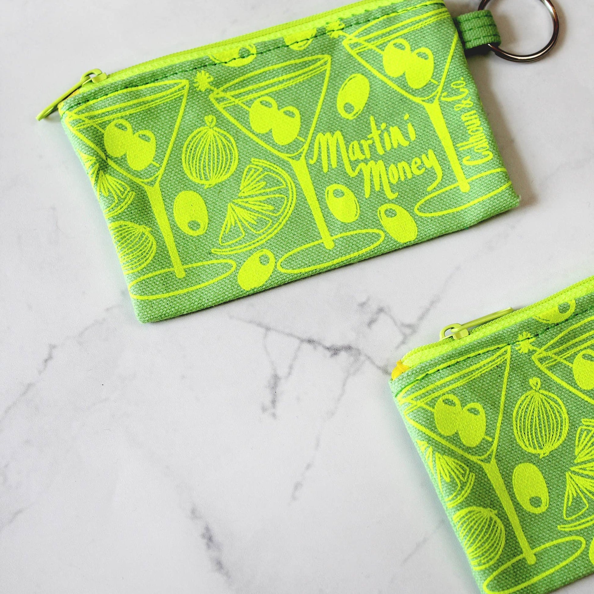 Bright green with bright lime green printing. Martini money pouches with olives, onions, and citrus. Keyring attached. text that reads: Calhoun & Co.