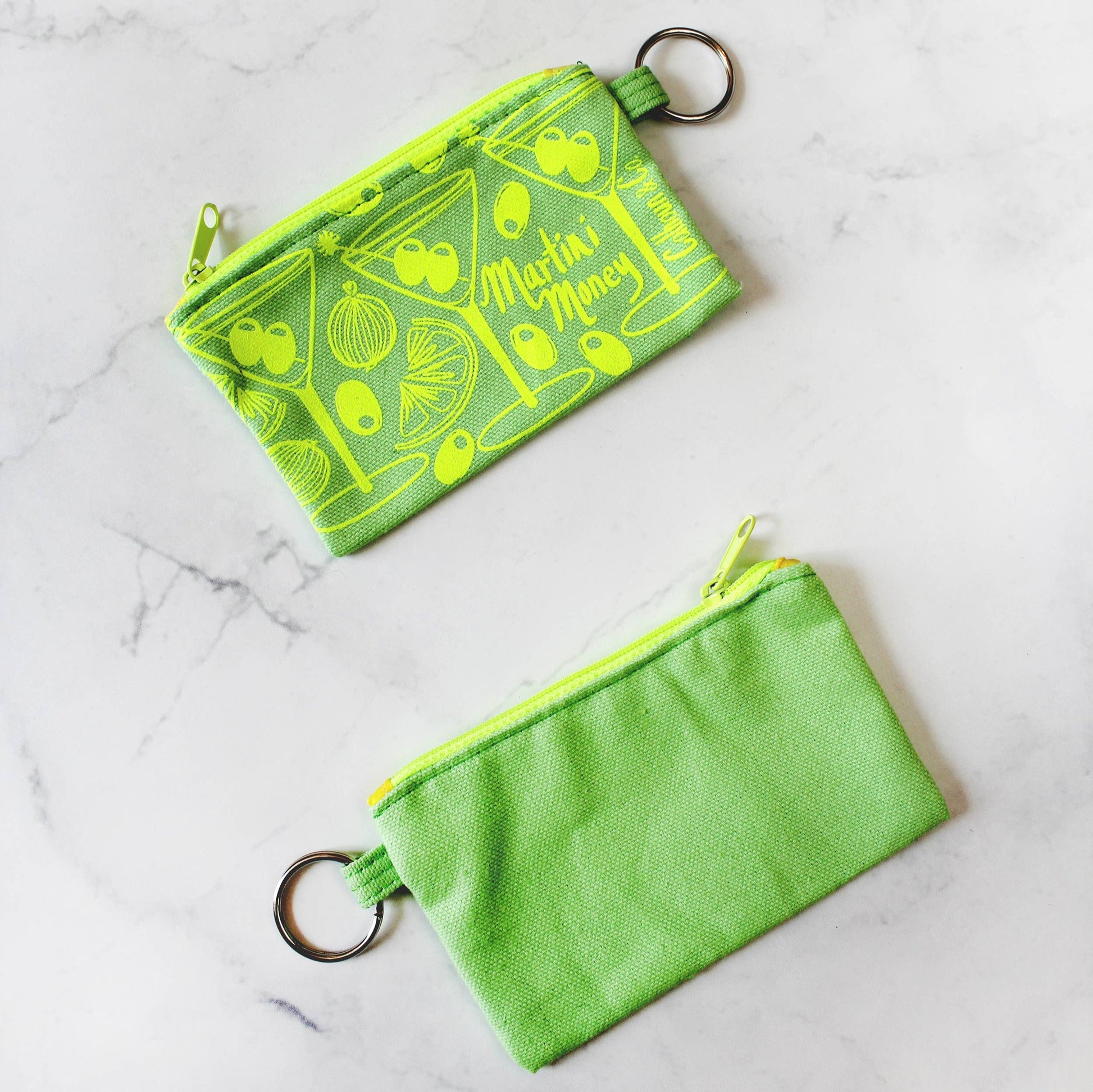 Bright green with bright lime green printing. Martini money pouches with olives, onions, and citrus. Keyring attached. text that reads: Calhoun & Co.