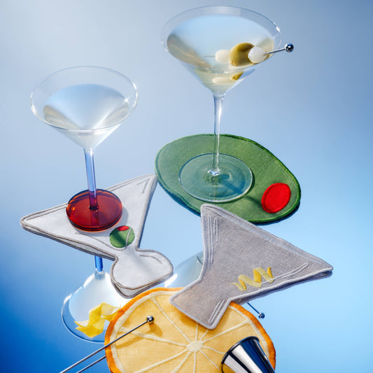 Set of cocktail glasses with garnishes on a blue background showcasing cocktail napkin set