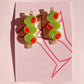Pair of olive trio hair clips with green and red accents on a pink card