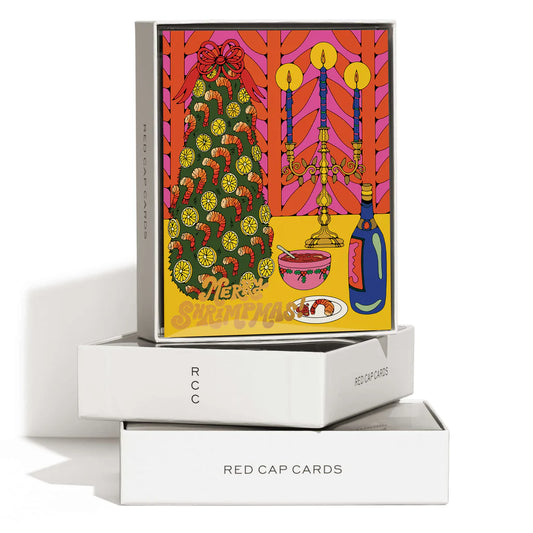 Boxed Set (white box with black writing) featuring holiday greeting card that reads "Merry Shrimpmas" -- Christmas tree is decked with shrimp and lemon slices, bowl of cocktail sauce, champagne bottle and candelabra 