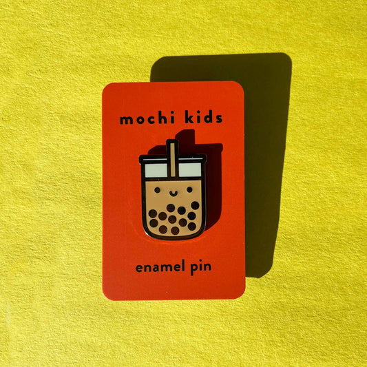 Enamel pin packaging with 'mochi kids' branding on a yellow background