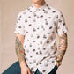 White button up shirt with tortoise buttons. Patterned with skulls, donuts, coffee and eyes. Male model with lots of tattoos.
