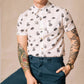 White button up shirt with tortoise buttons. Patterned with skulls, donuts, coffee and eyes.  Male model with tattoos.