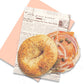 Bagel and lox designed post card on top of a newspaper envelope background