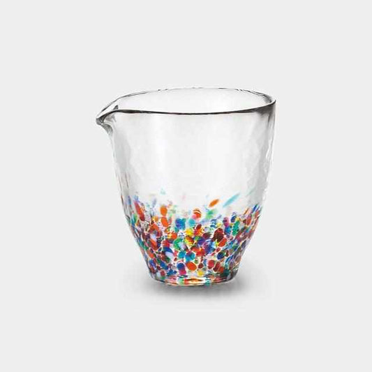 Clear glass pitcher with multicolored speckles on a white background