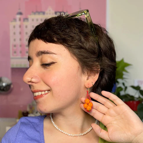 Oranges in mesh bag earrings worn on person 
