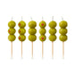 Six skewers with green olives and red stones on a white background