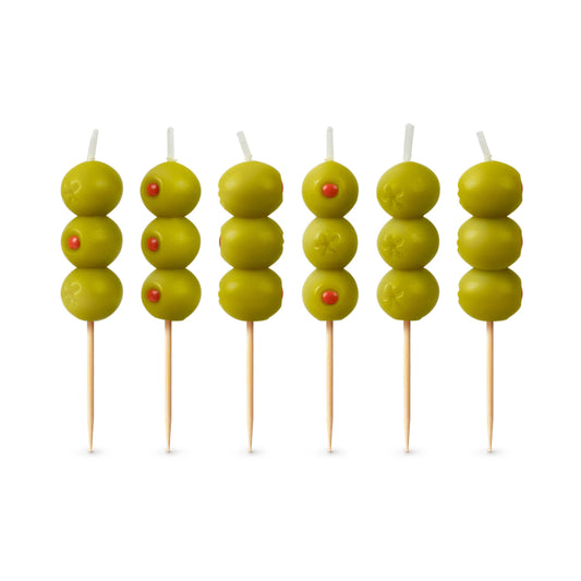 Six skewers with green olives and red stones on a white background