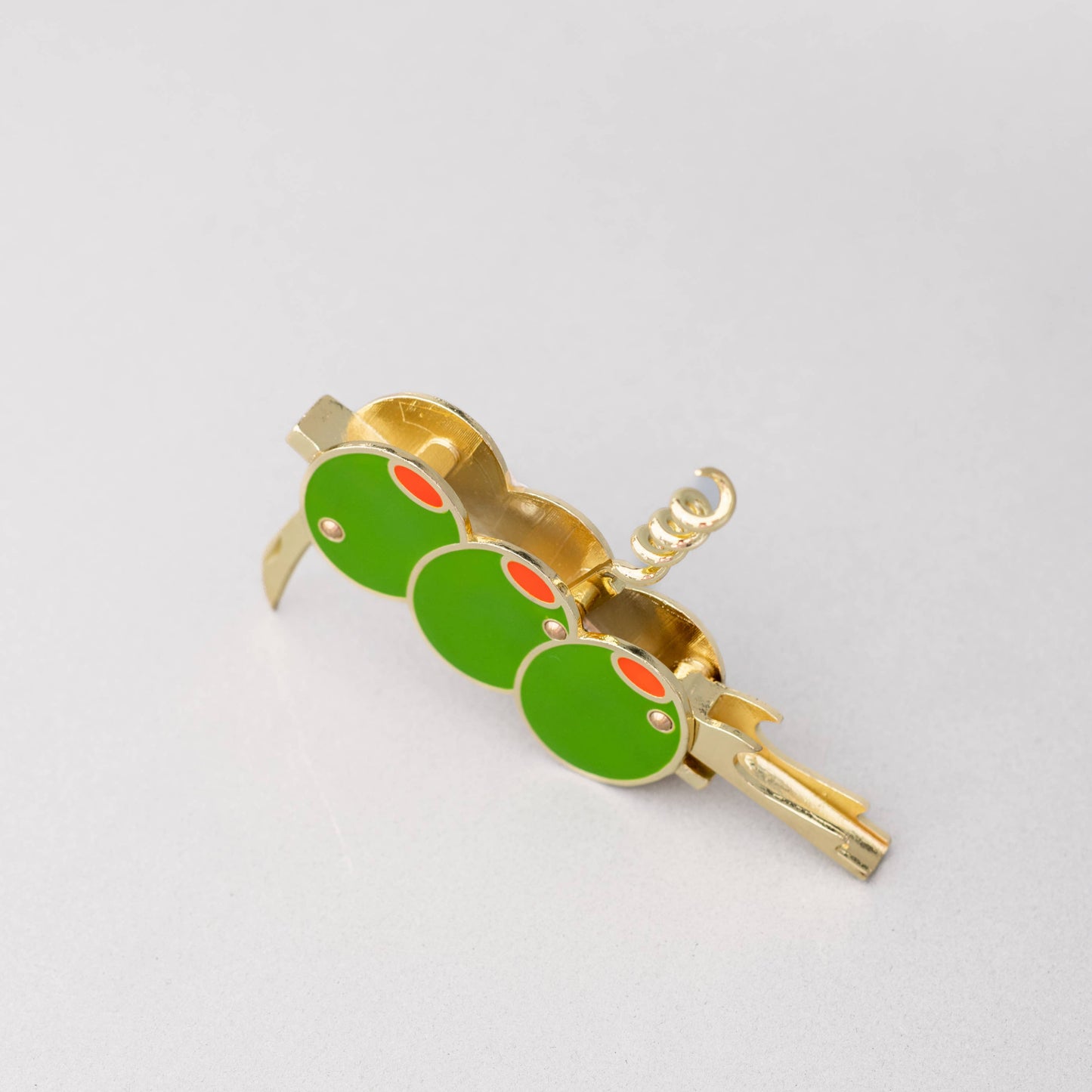 Gold and green olive corkscrew on a light gray background