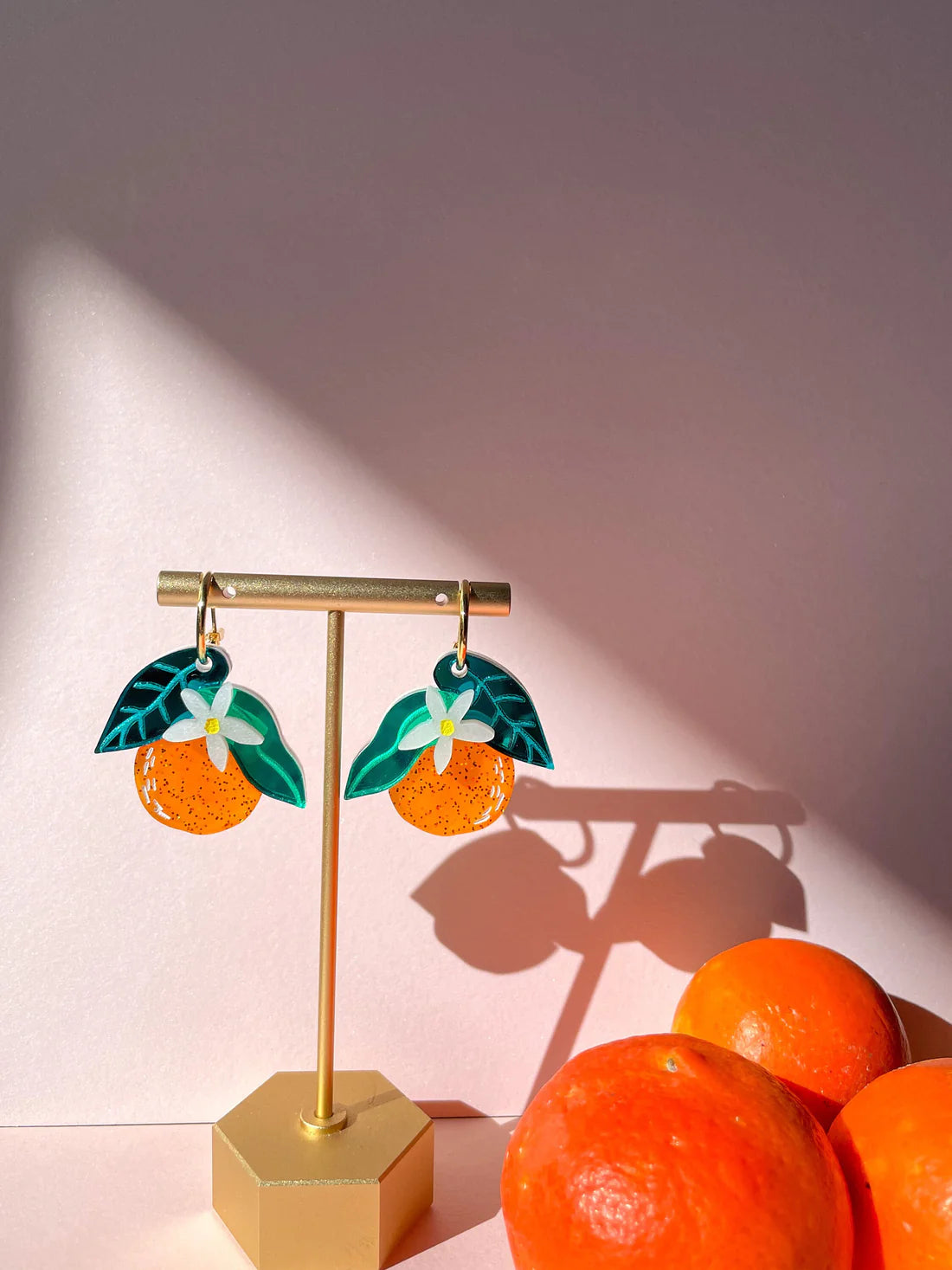 acrylic orange dangle earrings on jewelry stand 