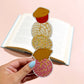 Colorful sweet mexican pastries bookmark held by a hand with a pink background