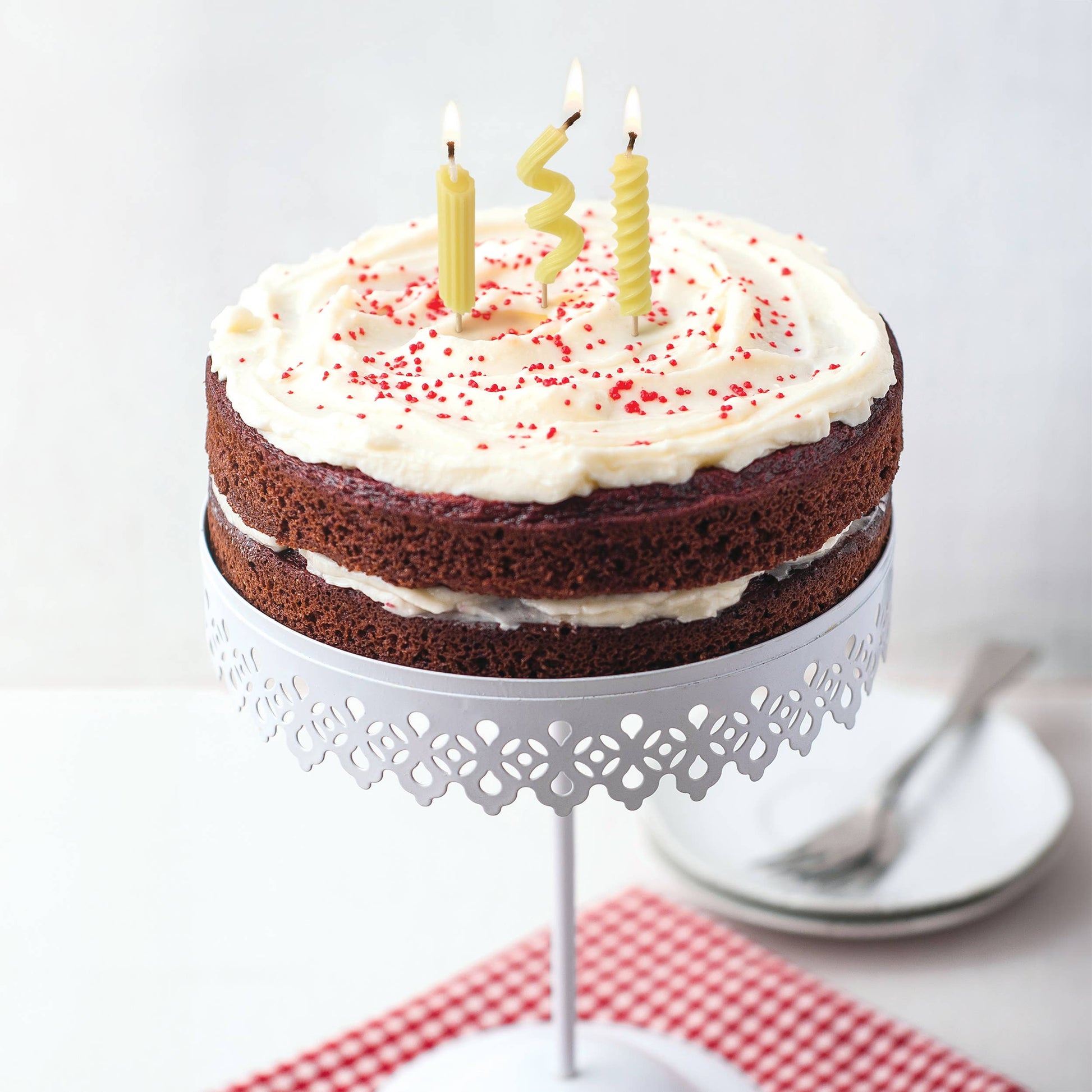 Chocolate cake with white frosting and red sprinkles on a pedestal 