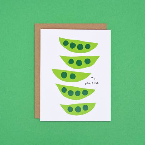 Greeting card with graphic print of five fresh green pea pods in a row. A small arrow points to a pod with two individual peas, text next to it reads "you + me."