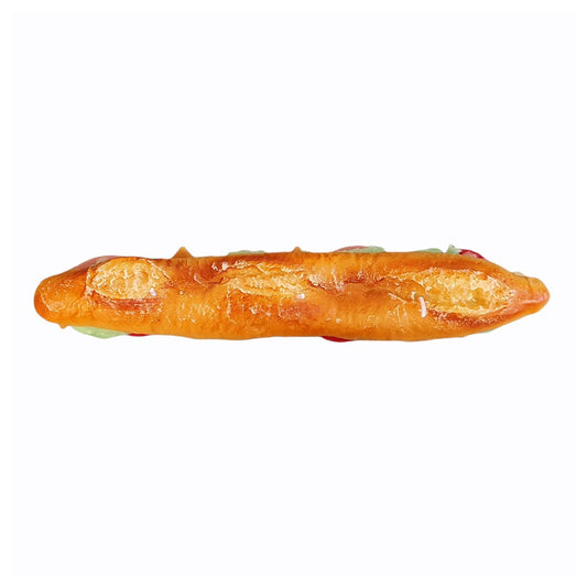 Wax candle shaped like a whole baguette sliced lengthwise and made into a hearty sandwich with many fillings. View from the top showing detail on the baguette.