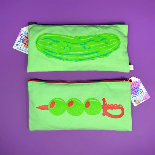 Two green pouches with pickle and cocktail olive designs on a purple background