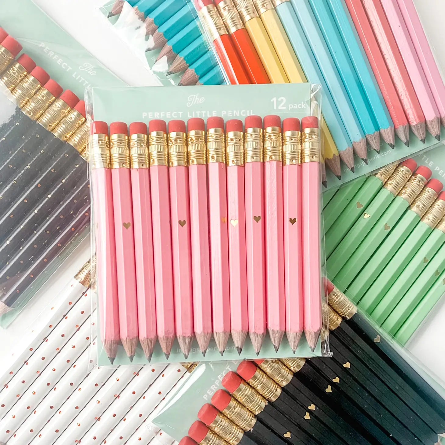 Several different 12-pack pencil packs stacked on eachother. Pencil packs range from black, white, pink teal, blue and rainbow. 