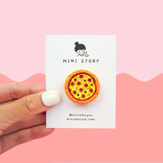 Hand holding a card that has a Pizza Magnet adhered to it. The text on the card has the business name which is Mini Story.