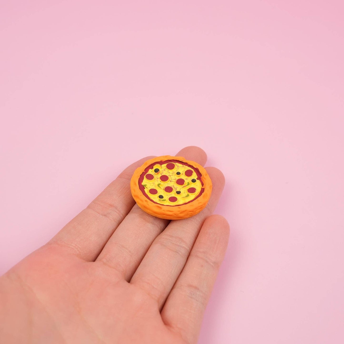 Pizza magnet on a hand to show the size detail.