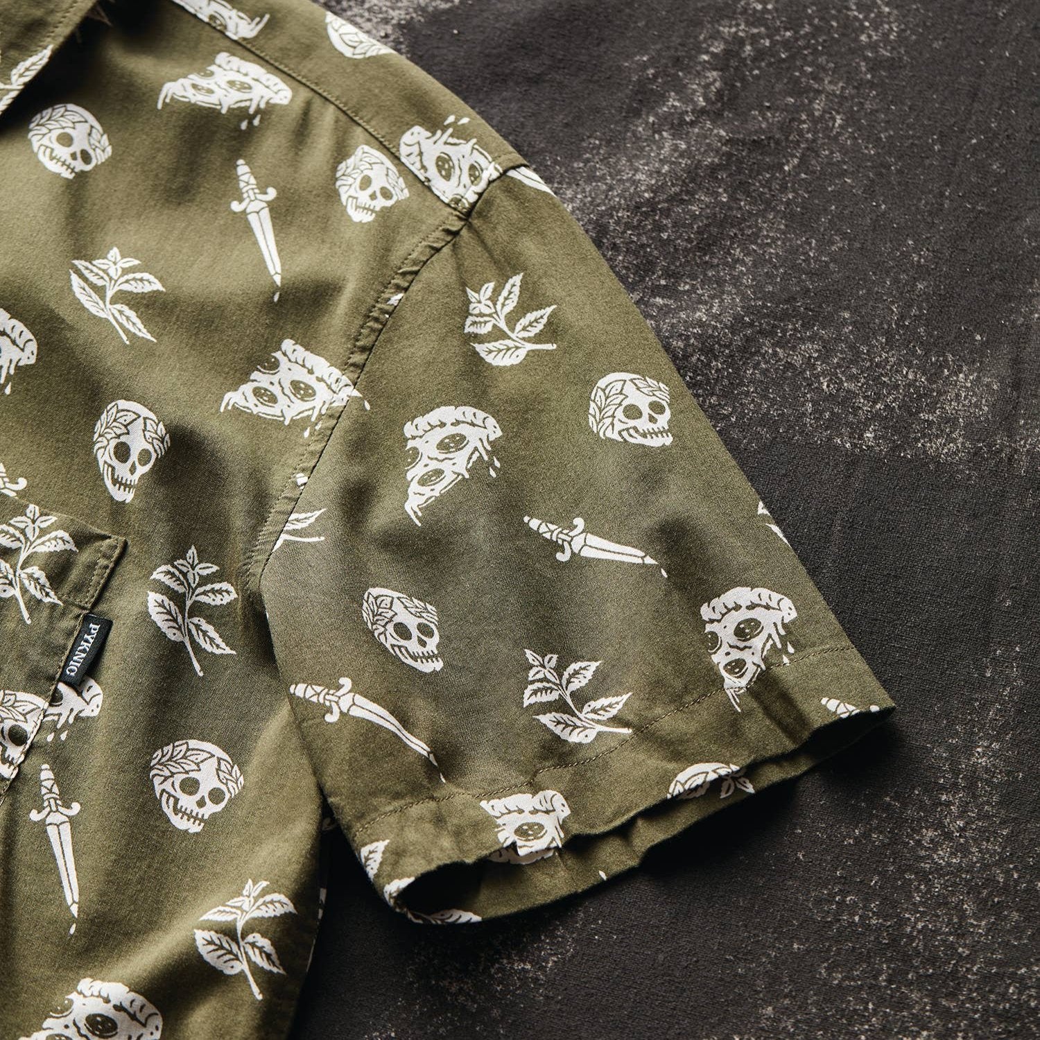 button up shirt that is oregano green with skulls, pizza and swords on it. 