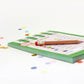 Notebook with colorful confetti and a pen on a white background