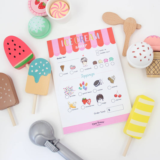 Ice cream shop pretend play order form with toy ice cream cones and utensils on a white background
