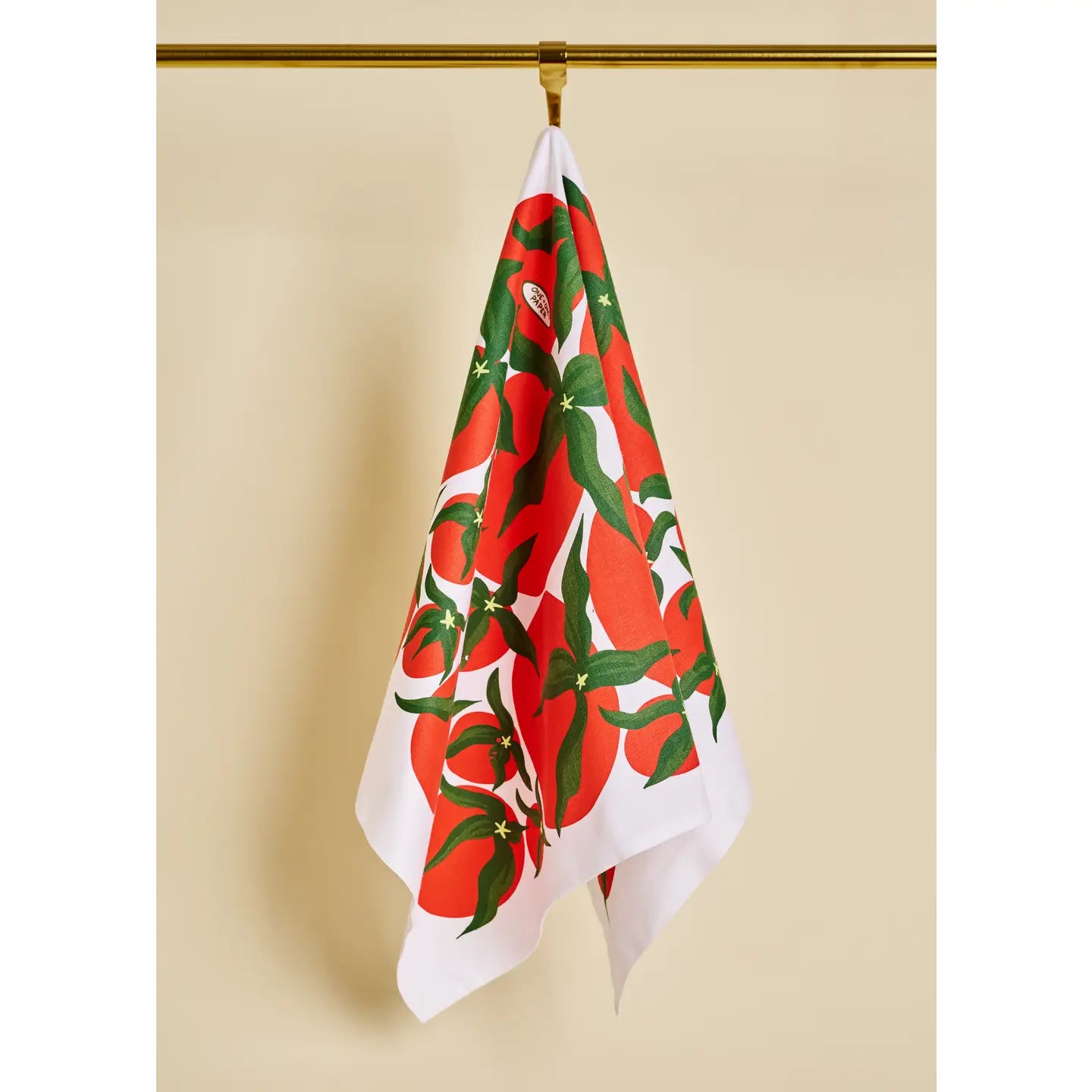 Decorative towel with red and green pattern hanging on a gold hook against a beige wall.