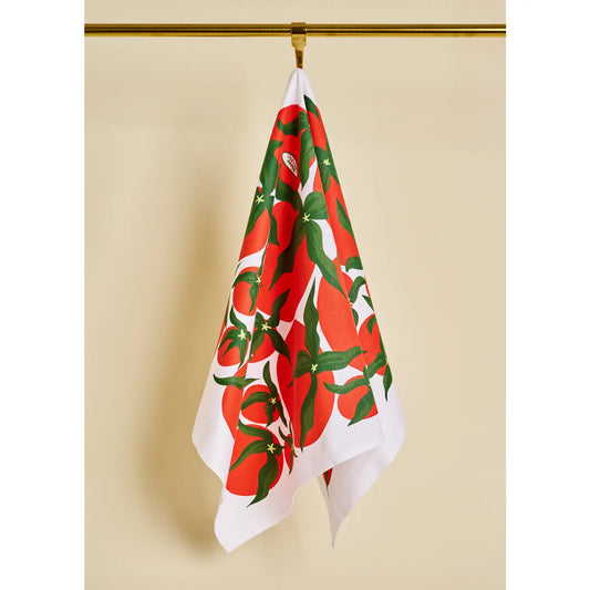Decorative towel with red and green pattern hanging on a gold hook against a beige wall.