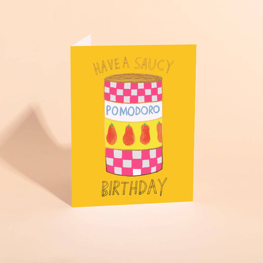 Birthday card with a can of Pomodoro  tomatoes on a yellow background and text that reads "Have a Saucy Birthday"