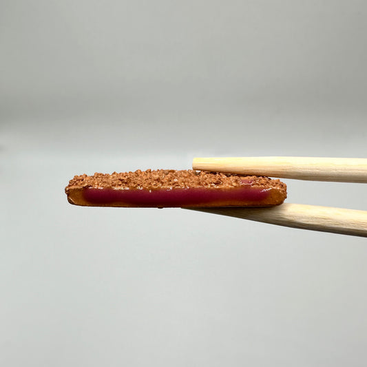 Pork Cutlet Chopstick Rest being held between a pair of chopsticks