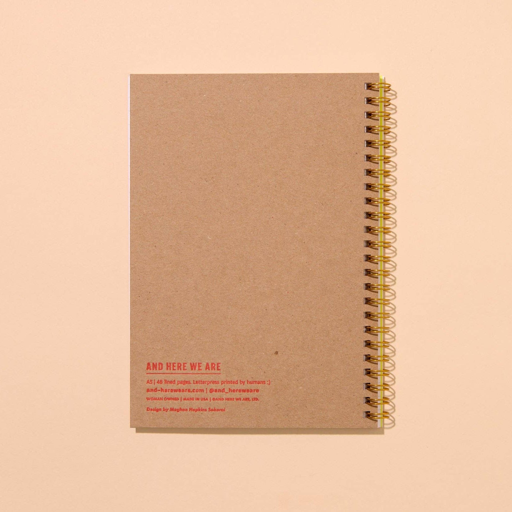 Brown notebook with gold spiral binding on a beige background