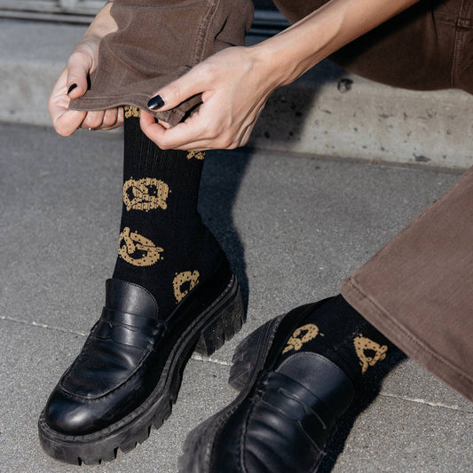 Model wearing pretzel socks cuffing her pant as an action shot.