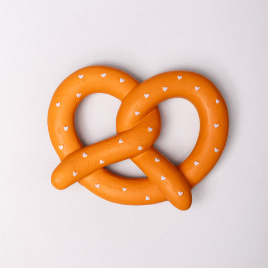 Orange pretzel-shaped object with white heart patterns on a light gray background
