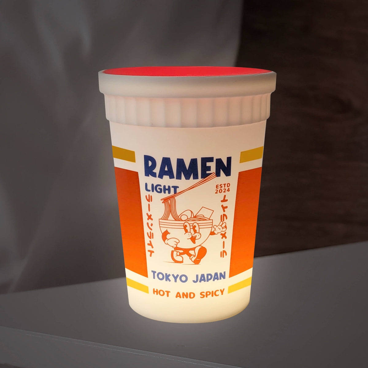 Light-up ramen cup with text and graphics on a dark background