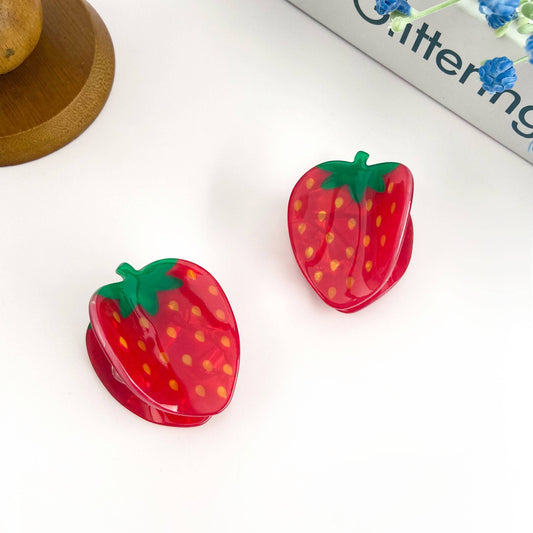 Two strawberry-shaped hair clips on a white surface.