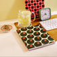 Notebooks with red and black circular patterns on a desk with a glass of water and clock.