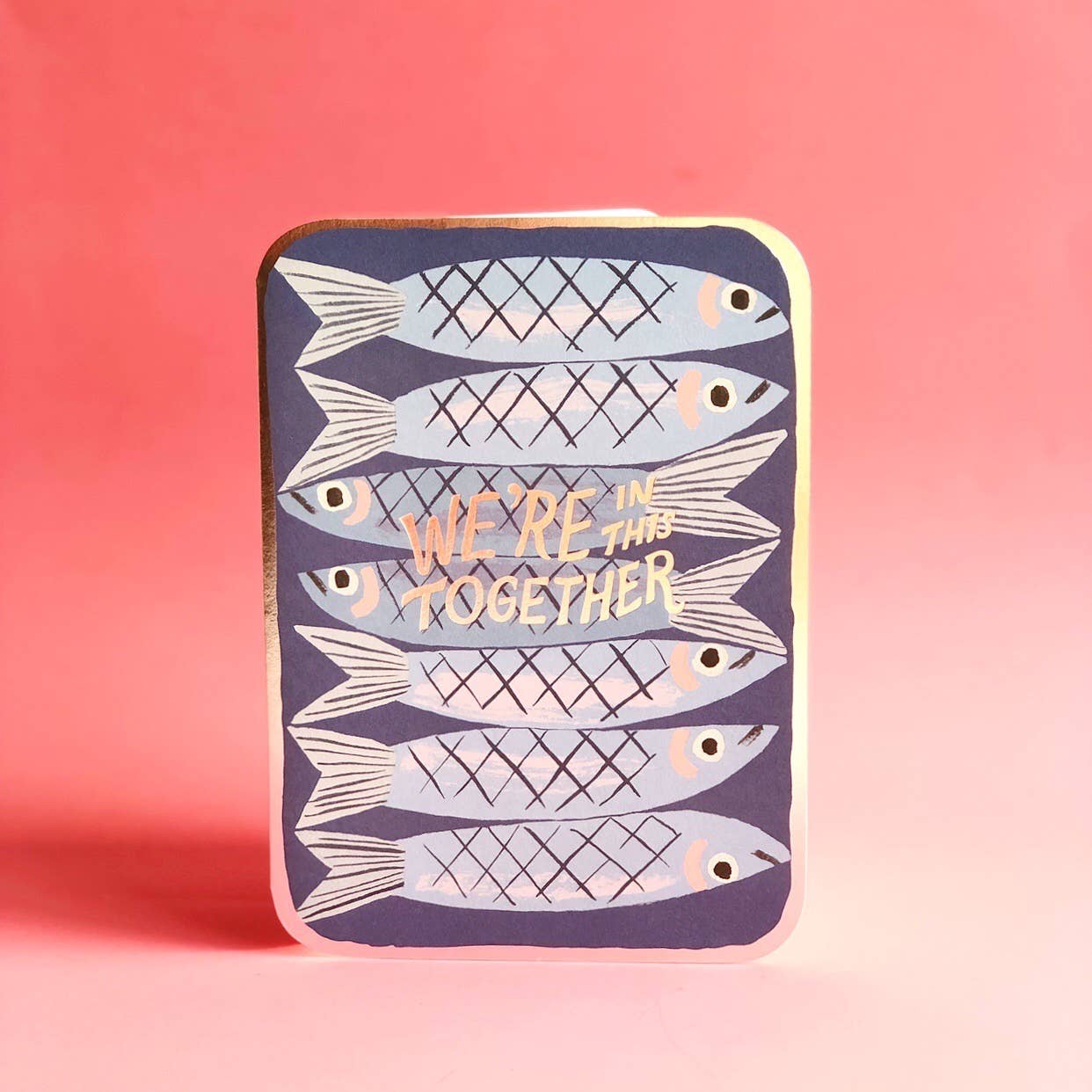 Encouraging greeting card with illustration of 7 sardines on blue background with text in silver foil "We're In This Together."