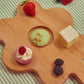 Floral shaped wooden cutting board with fruits and pastries on it 