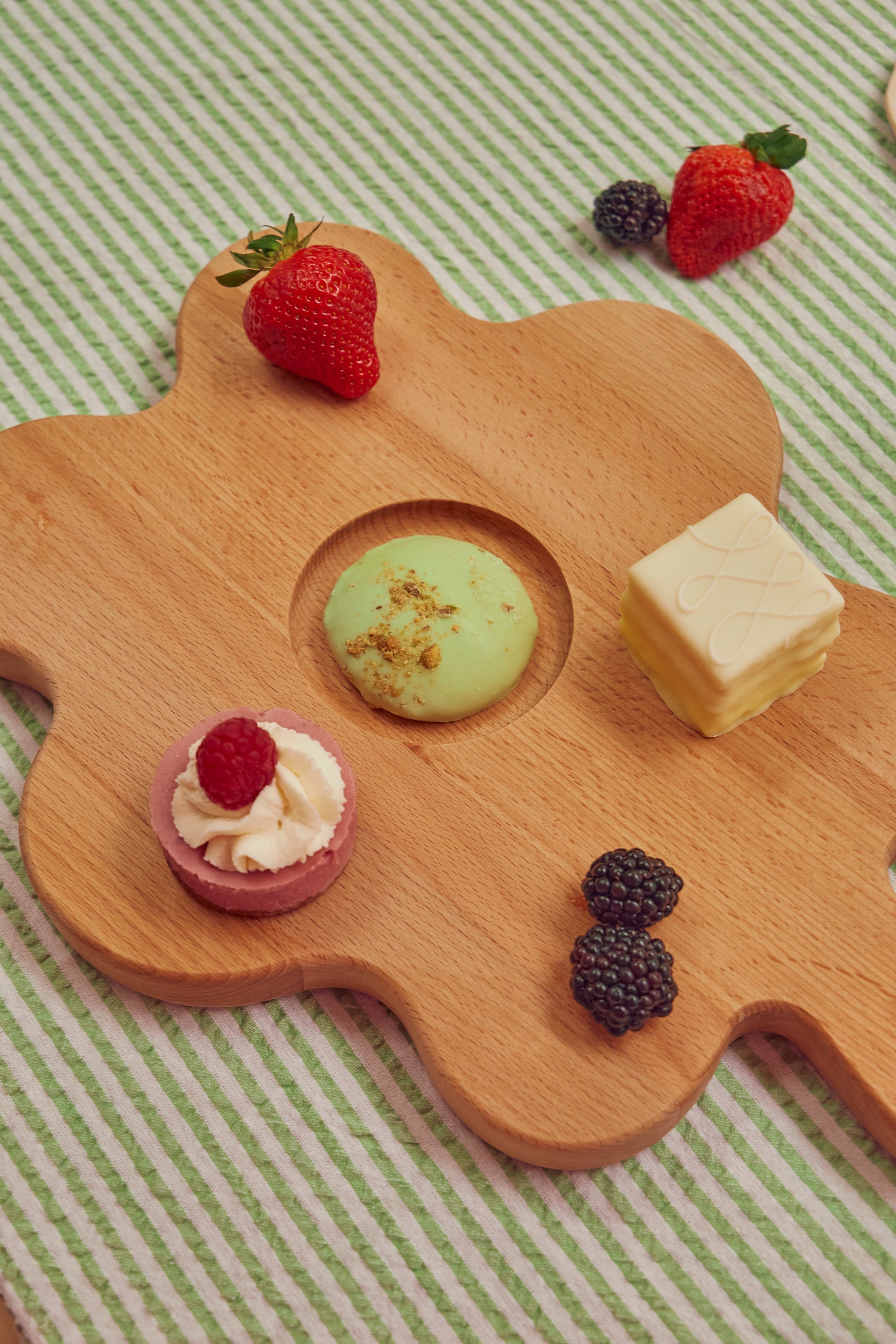 Floral shaped wooden cutting board with fruits and pastries on it 