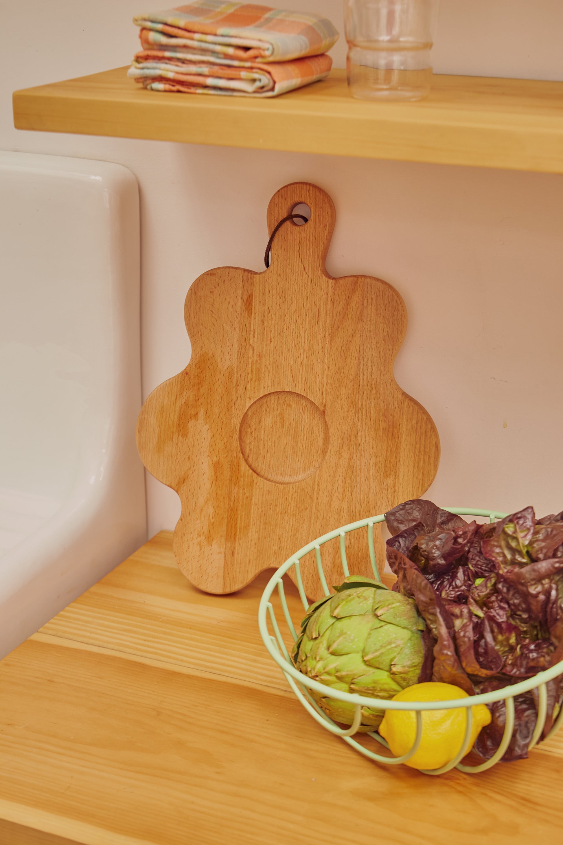 Floral shaped wooden cutting board standing against wall 