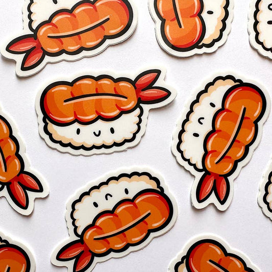 A close-up flat lay of cute cartoon sushi stickers on a white background. The stickers feature orange and red shrimp sushi pieces with white rice and black outlines.