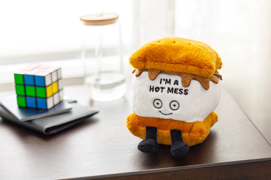 S'more plush toy sitting on a desk next to a rubiks cube.