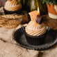 Realistic Smores Candle with chocolate cupcake base, whipped marshmallow topping and topped with a piece of chocolate and piece of graham cracker. Candle is lit.