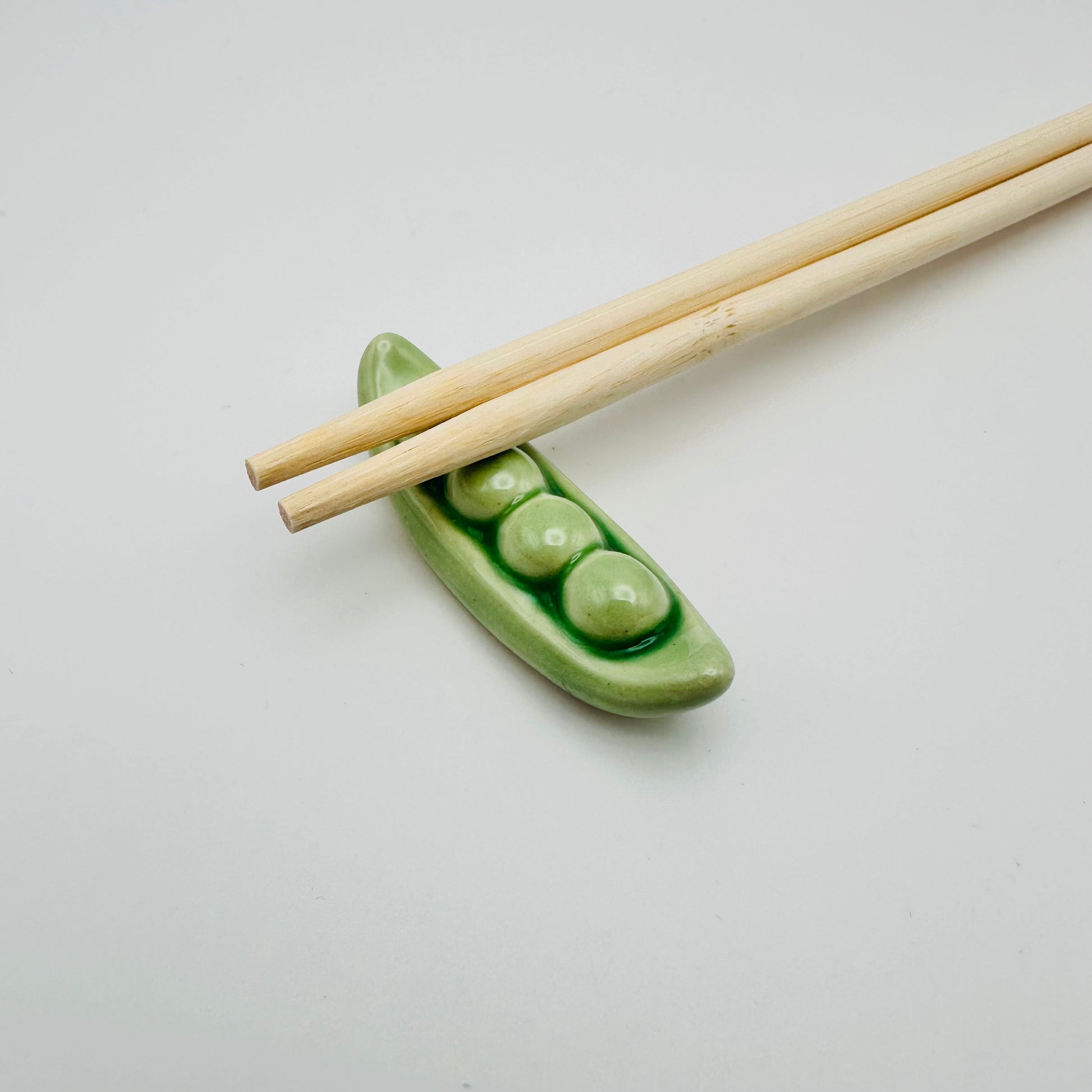 Snap Pea Chopstick Rest with a pair of chopsticks resting on them.