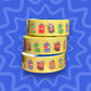 Three rolls of yellow washi tape with soda can designs on a blue wavy background